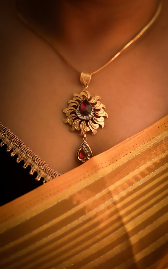 Stylish gold pendant with red gemstone elegantly displayed on a traditional Indian saree.